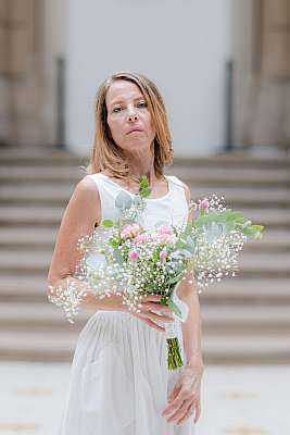 La mariée avec son bouquet pose dans la cours centrale de la mairie de Paris 18