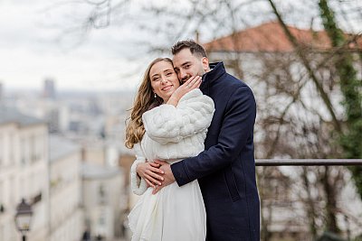 Séance photo de couple dans les escalier de Montmatre offrant une vue imprenable sur Paris