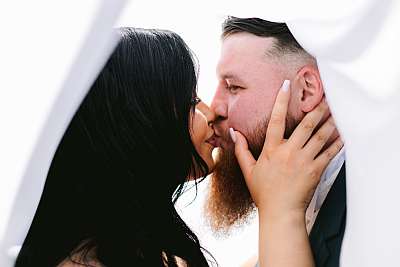 Les mariés s'embrassent sous le voile de la mariée