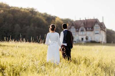 Les mariés main dans la main devant le château