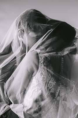 Photo de couple douce et romantique des mariés sous le voile de la mariée