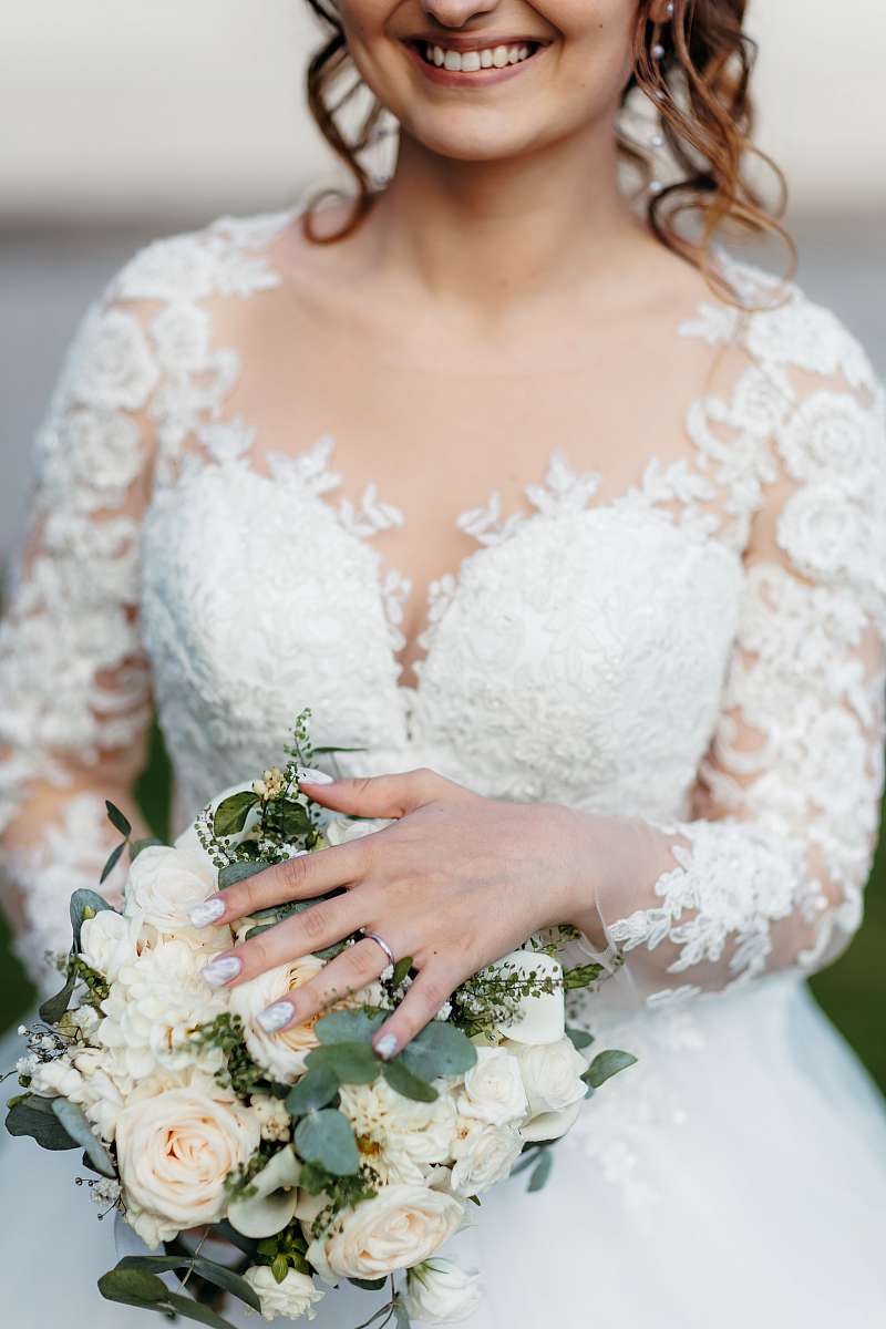 Gros plan sur l'alliance de la mariée et de son bouquet de fleurs