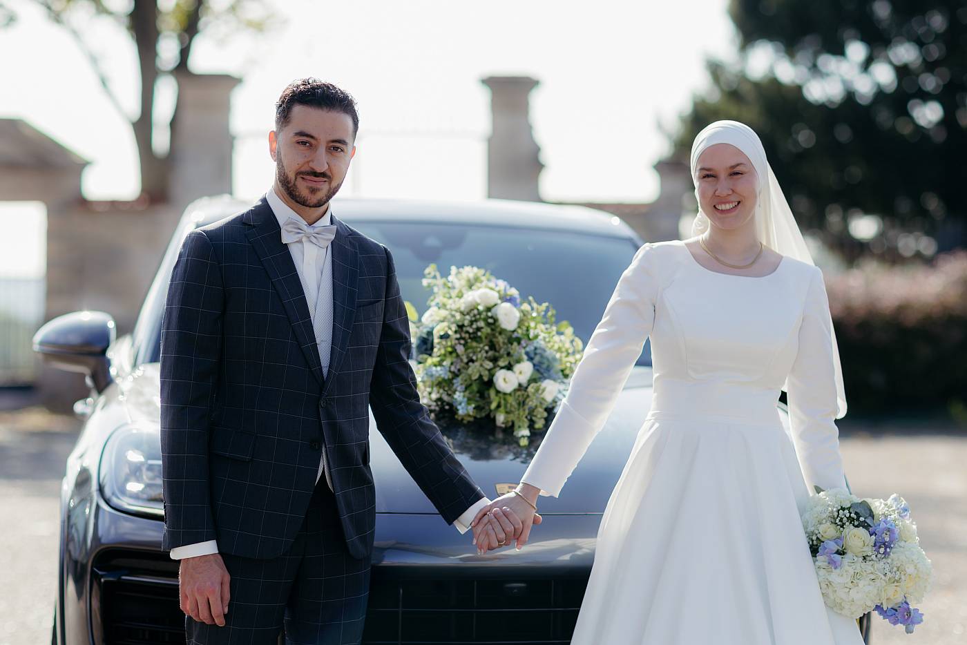 Photo des mariés devant la voiture décorée