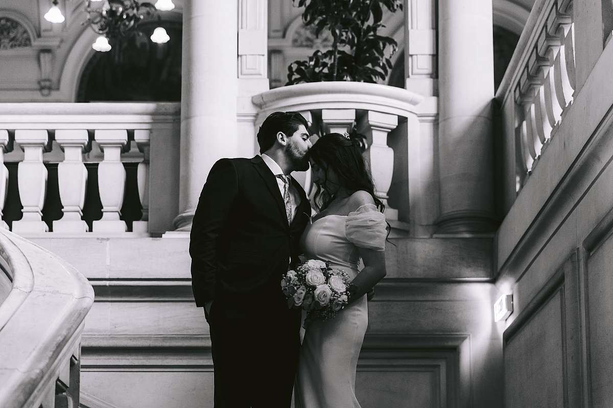 Baiser sur le front de la mariée dans les escaliers de la salle des mariages
