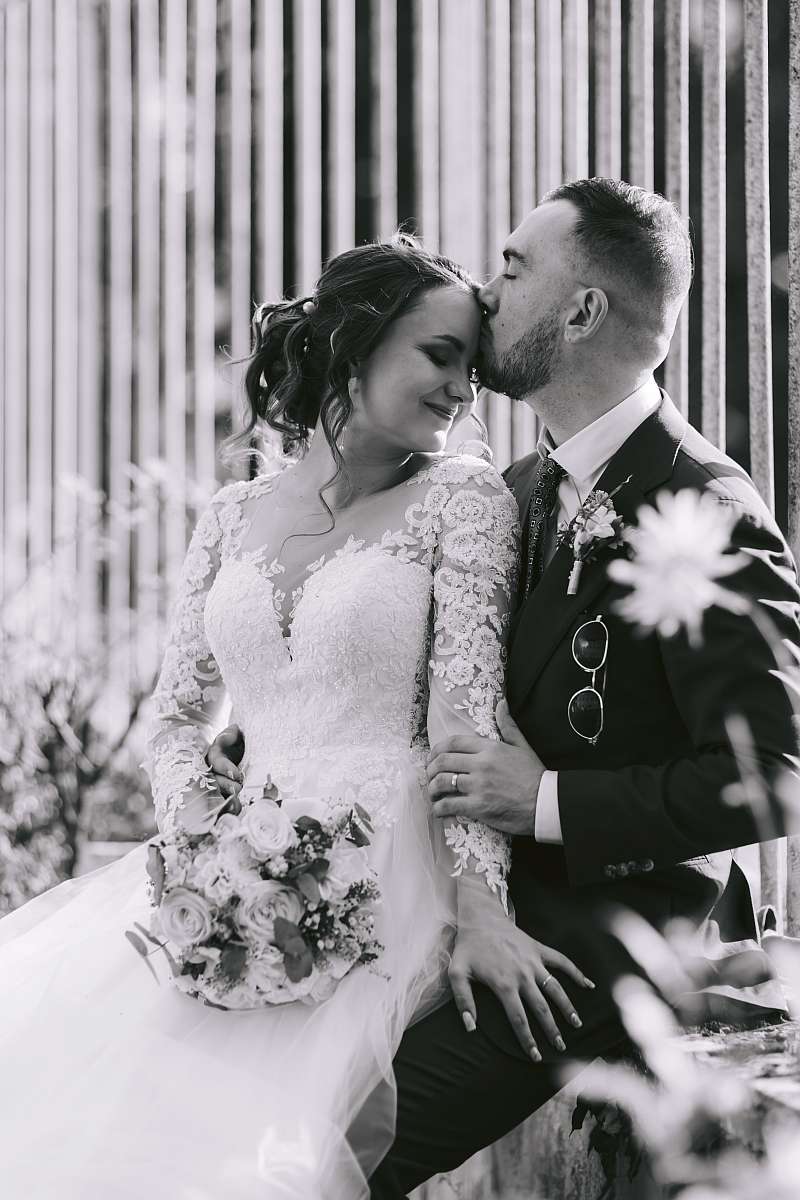 Le marié donne un tendre baiser sur le front de la mariée