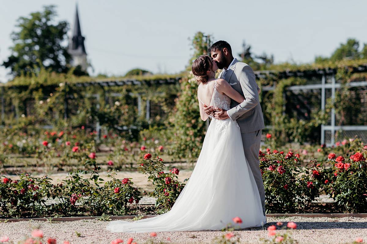 Pose romantique des mariés parmi les roses à la roseraie du Val-de-Marne