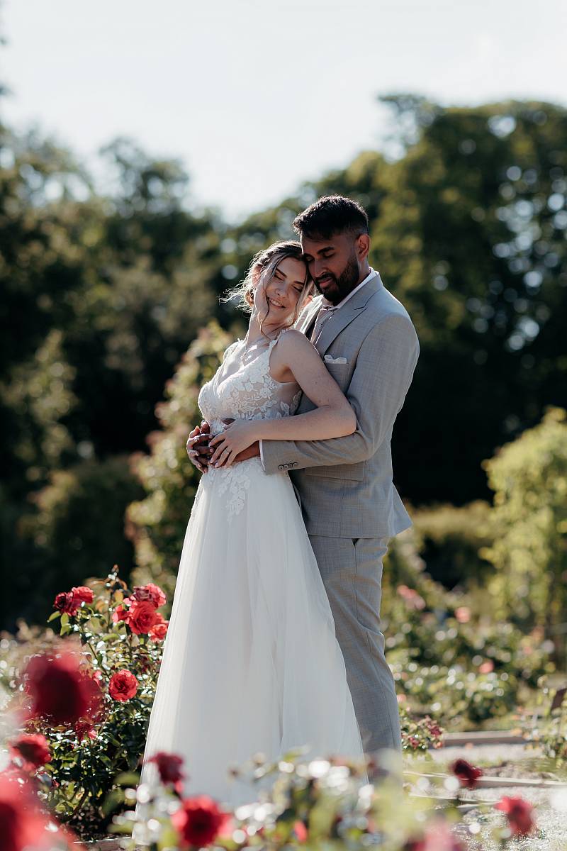 Portrait des mariés enlacés parmi les roses à la roseraie de l'Haÿ-les-Roses