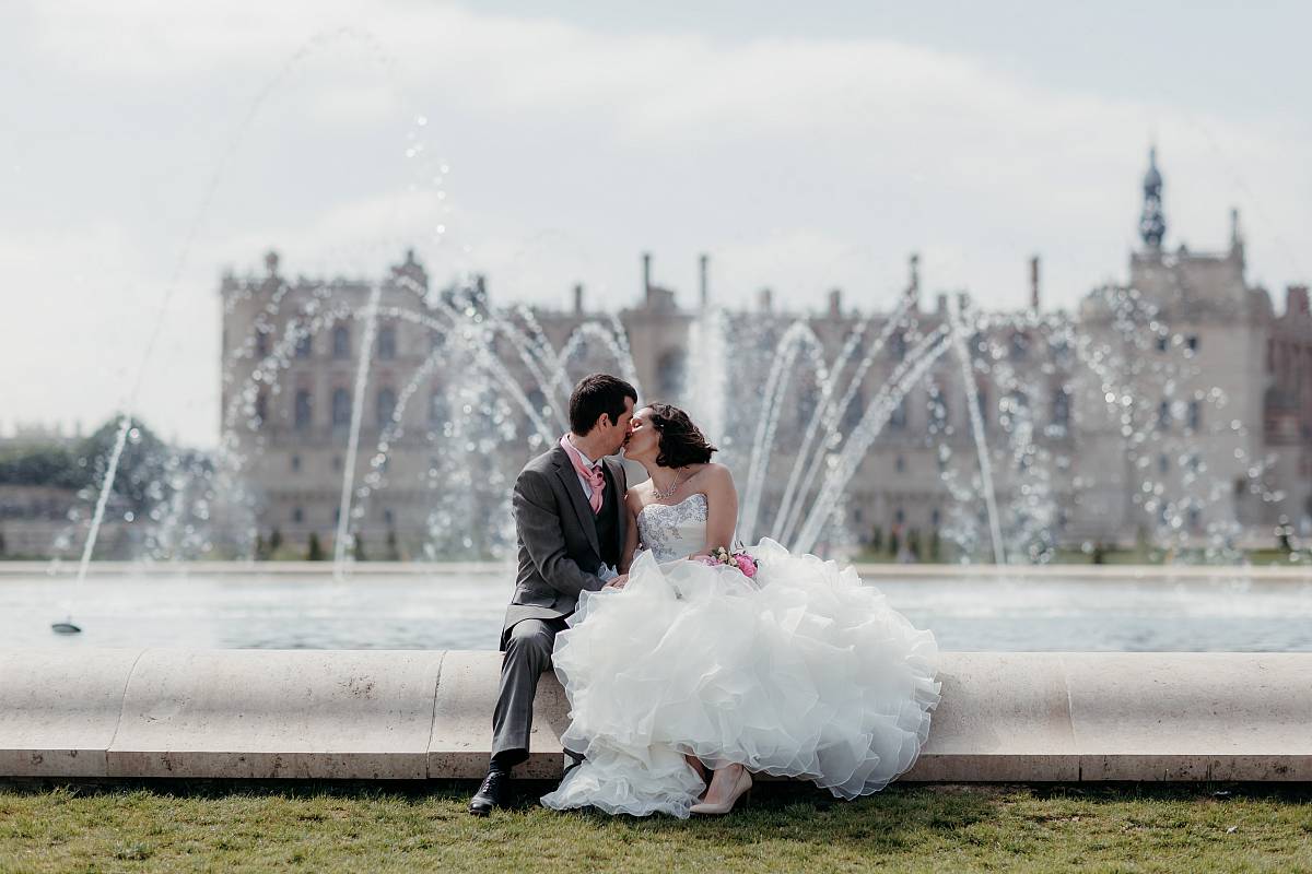 Baiser du couple avec les jets d'eau et le château en arrière plan