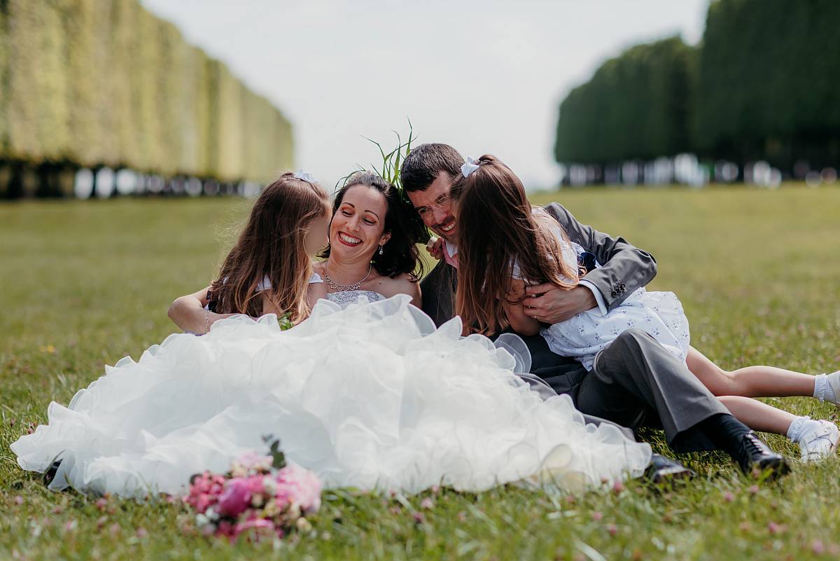 La parents et leurs filles s'amusent assis dans l'herbe