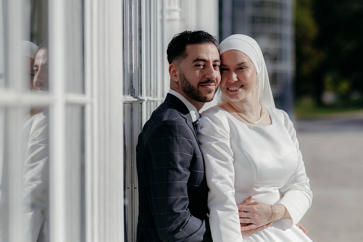 Photo formelle des mariés devant la façade blanche de l'orangerie