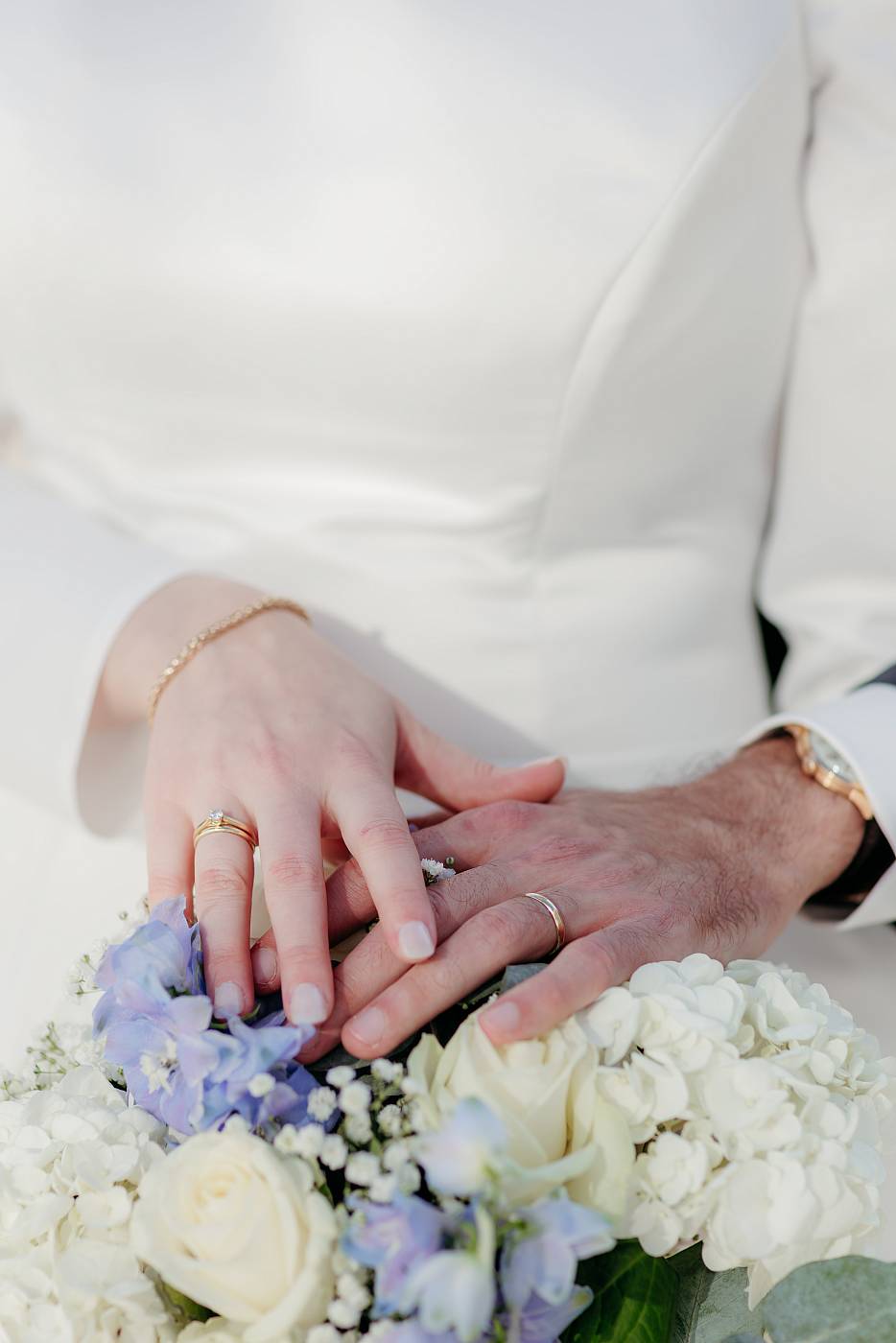 les mariés posent leurs main sur le bouquet de la mariée