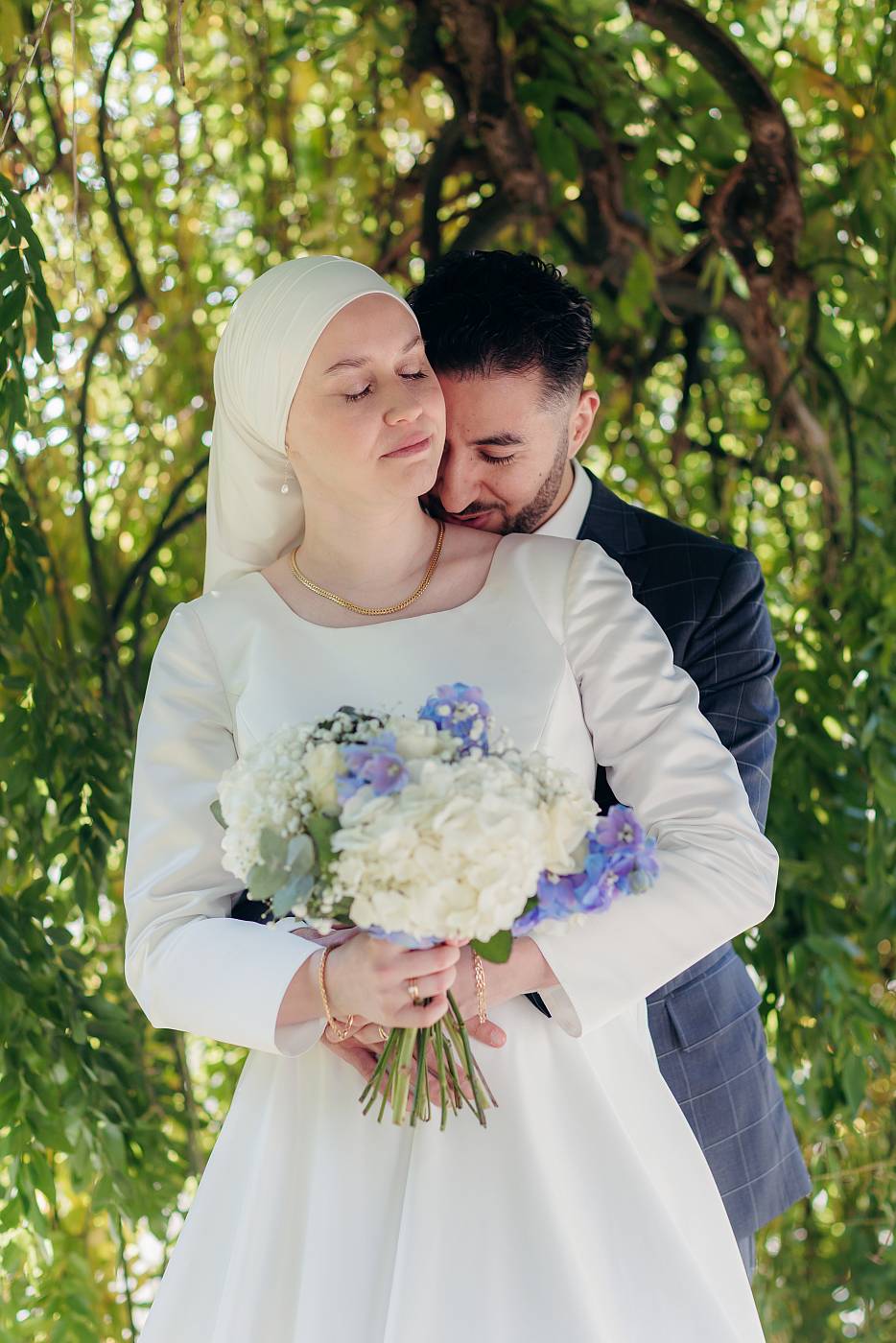 Les mariés partagent un moment de tendresse sous un saule pleureur