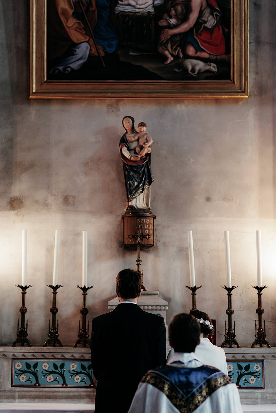 Les mariés et le prêtre devant la statue de la vierge