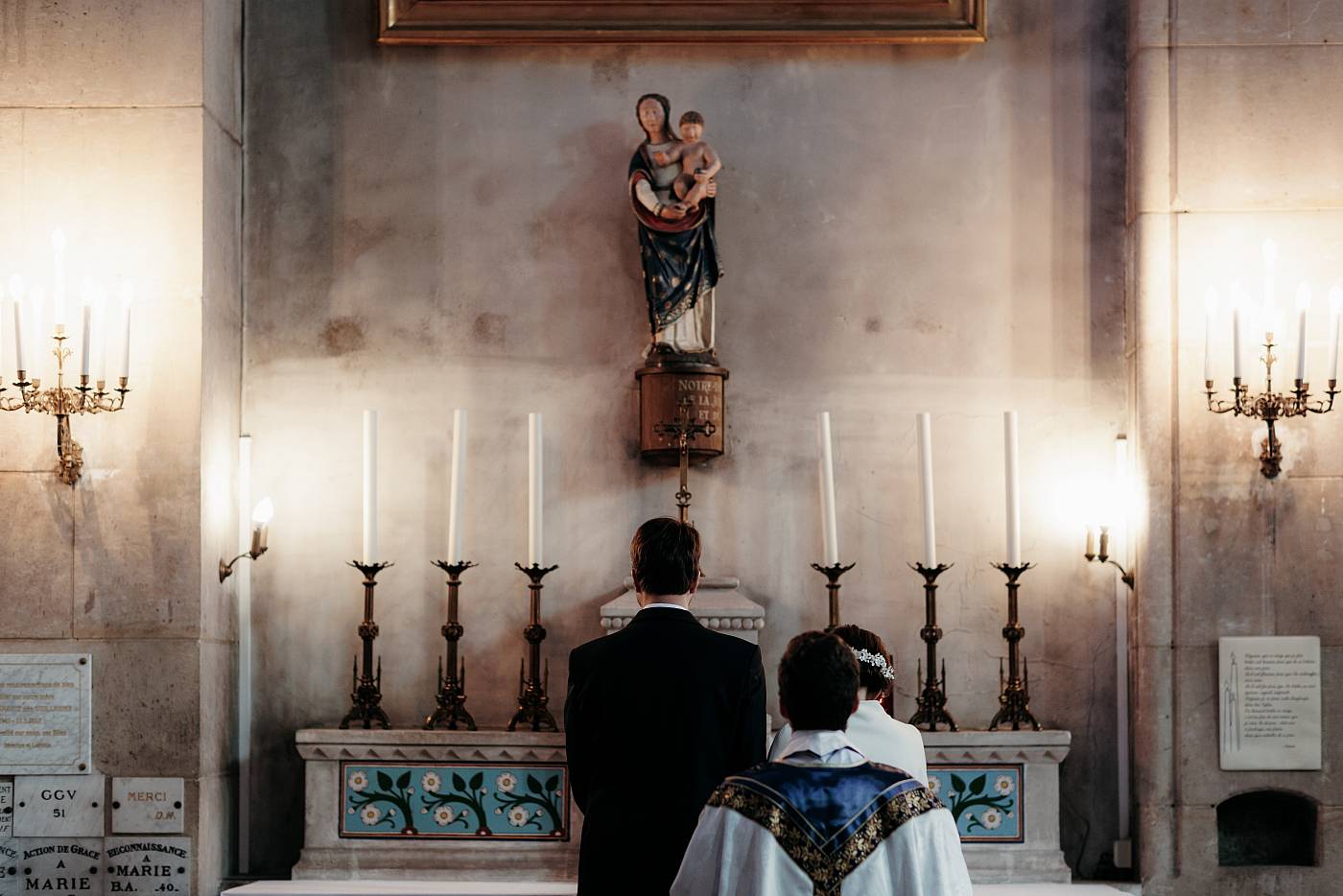 Les mariés de dos face à la statue de la vierge