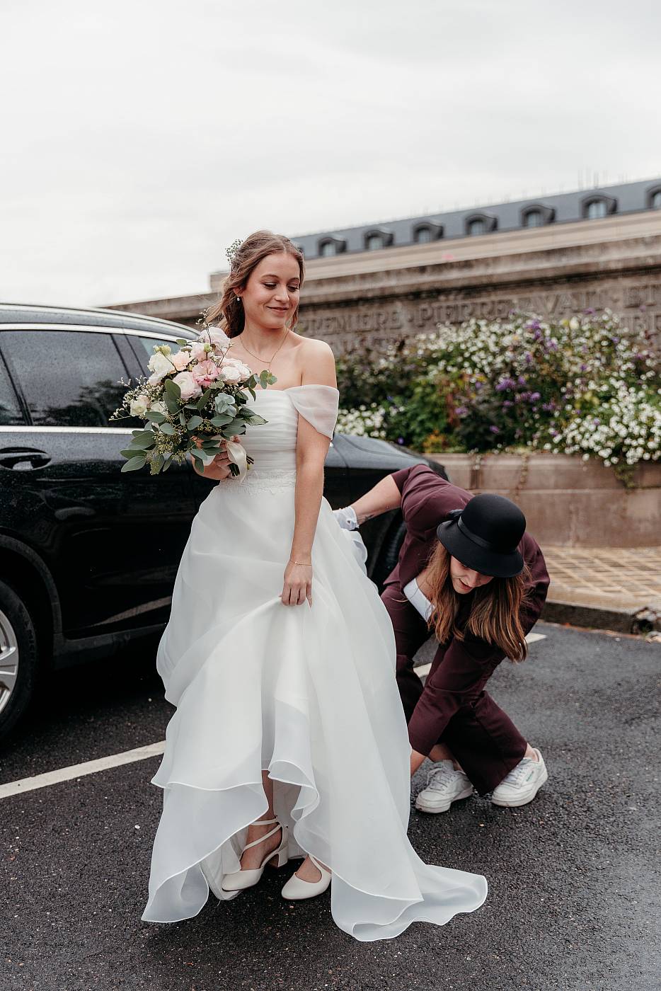 La mariée ajuste sa robe en sortant de la voiture