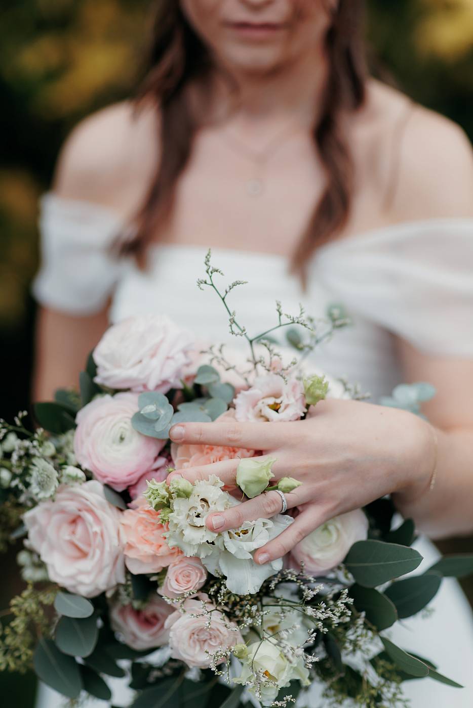 Gros plan sur la bague et le bouquet de la mariée