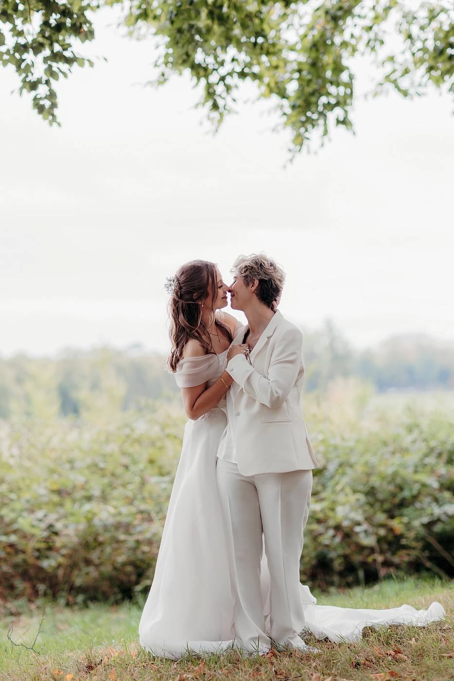 Baiser des mariées sous le feuillage d'un arbre
