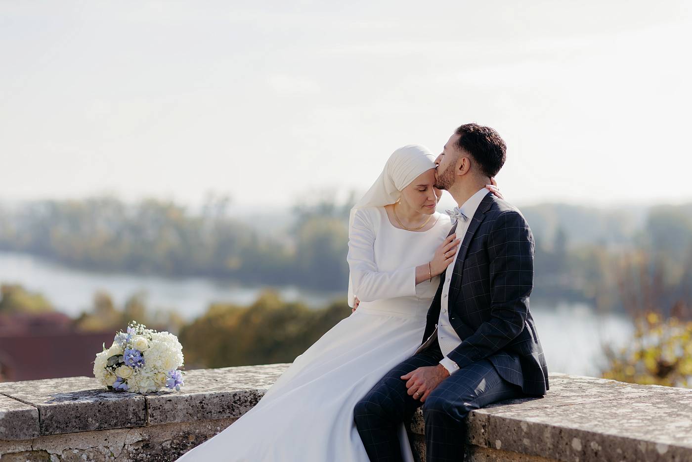 Baiser sur le front de la mariée avec un joli décor des Yvelines en arrière plan