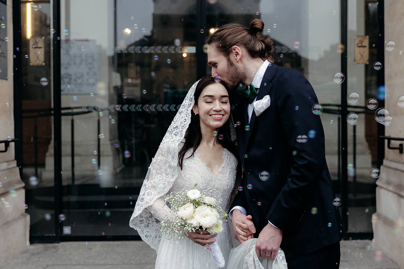 Petits baisers sur le front de la mariée tandis que les bulles de savon volent