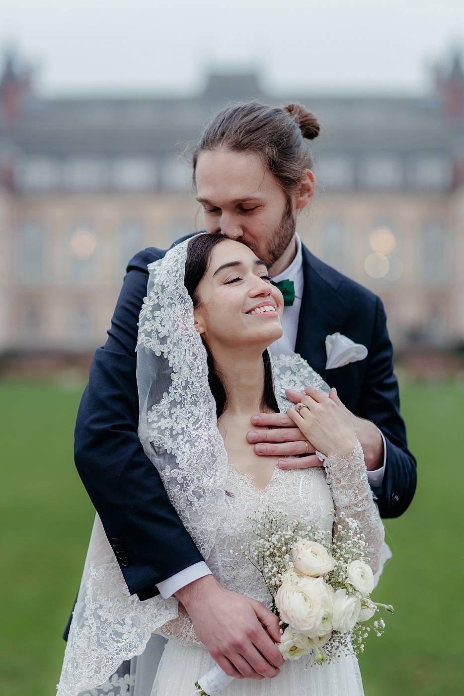 Petit baiser sur le front de la mariée avec la cité universitaire en toile de fond