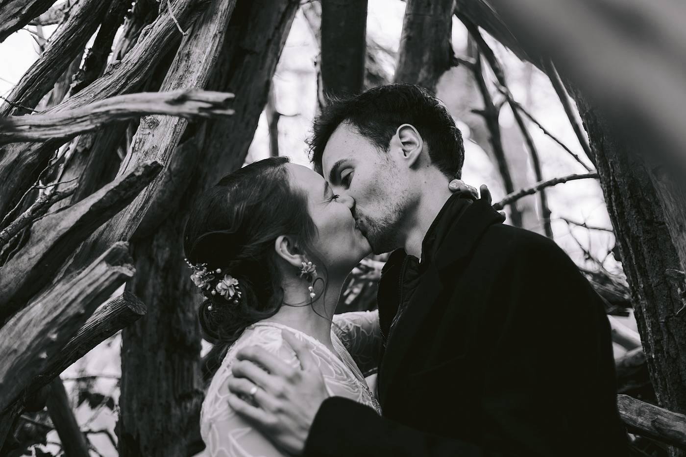 Baiser des mariés sous des branches de bois dans la forêt de Fontainebleau