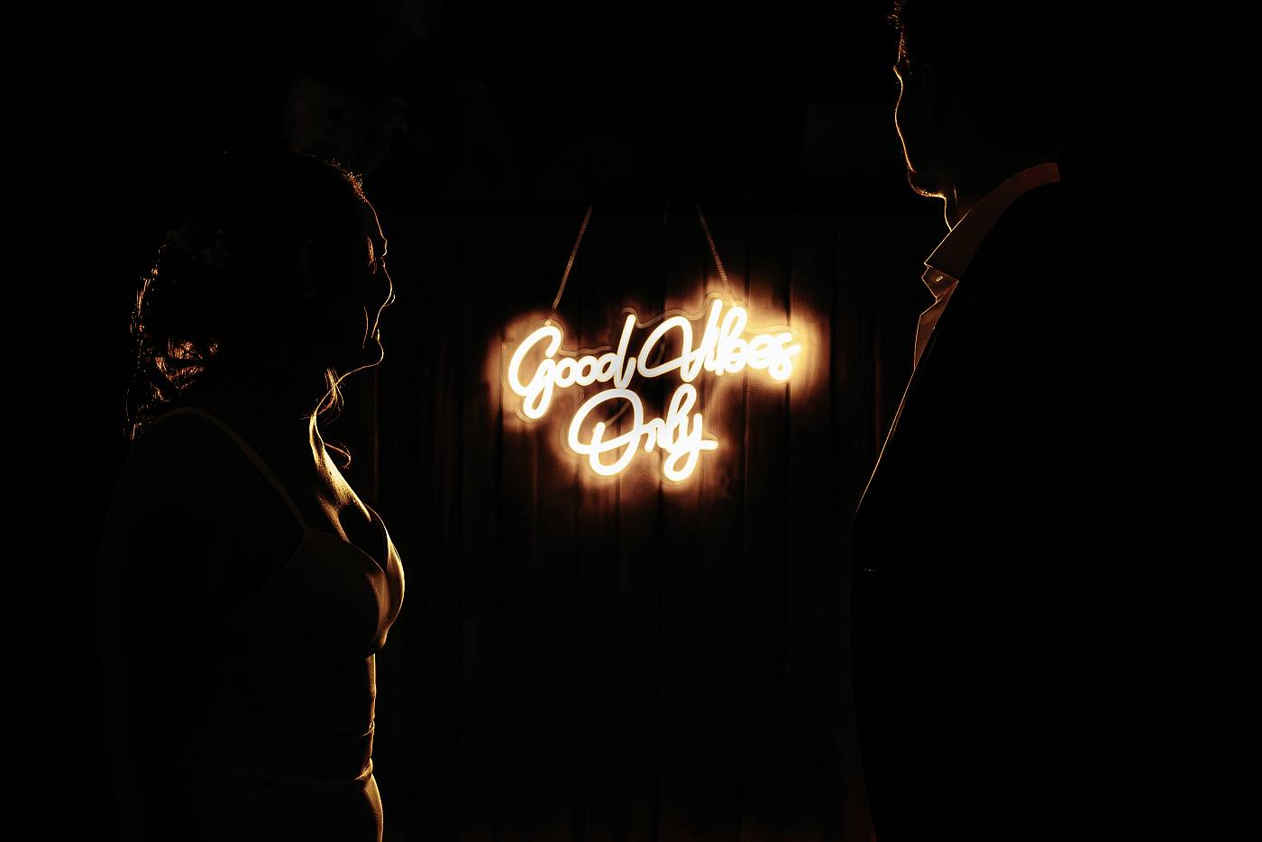 Les mariés en clair-obscur devant le logo du DJ