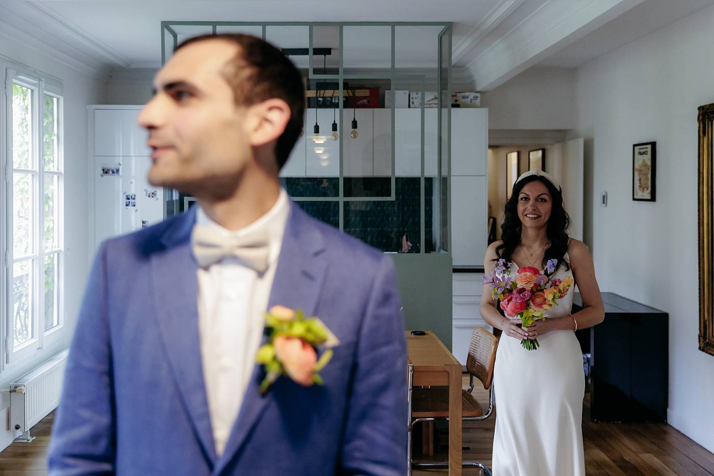 La mariée arrive avec son bouquet de fleurs dans le dos du marié