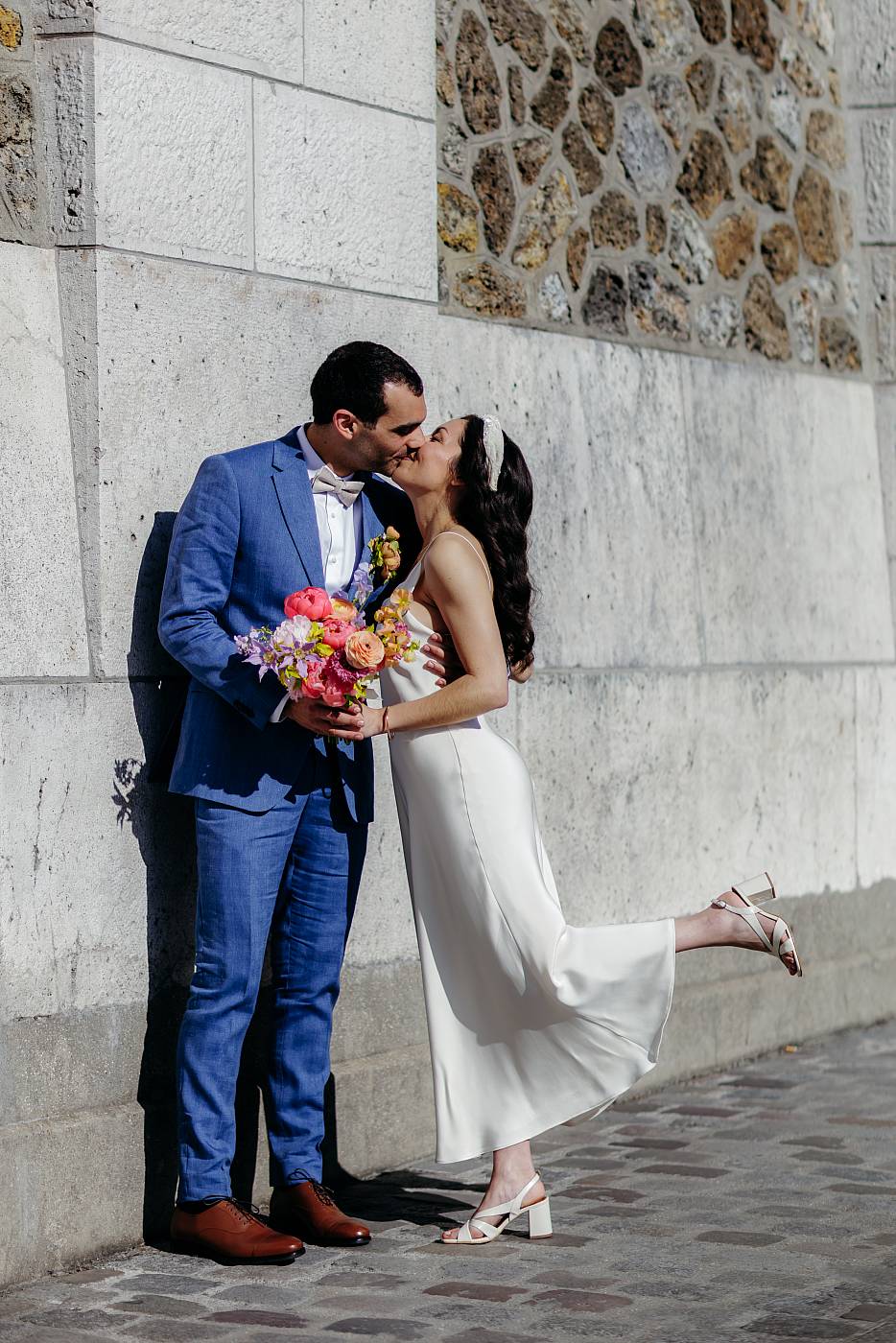 Baiser des mariés devant le réservoir de Montmartre sous le soleil d'avril