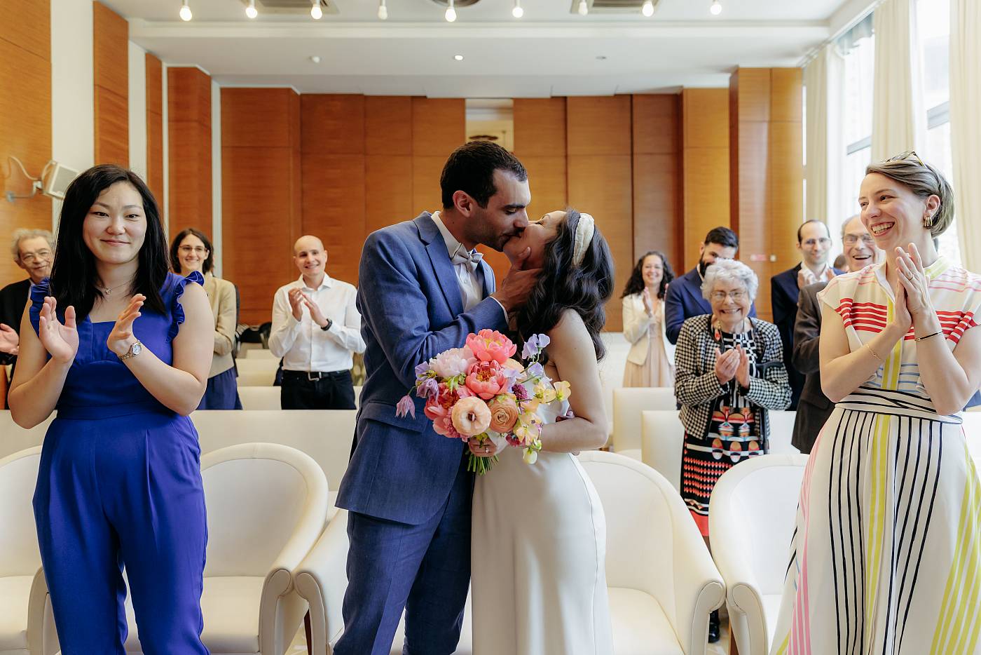 Le baiser des mariés tandis que leurs invités applaudissent