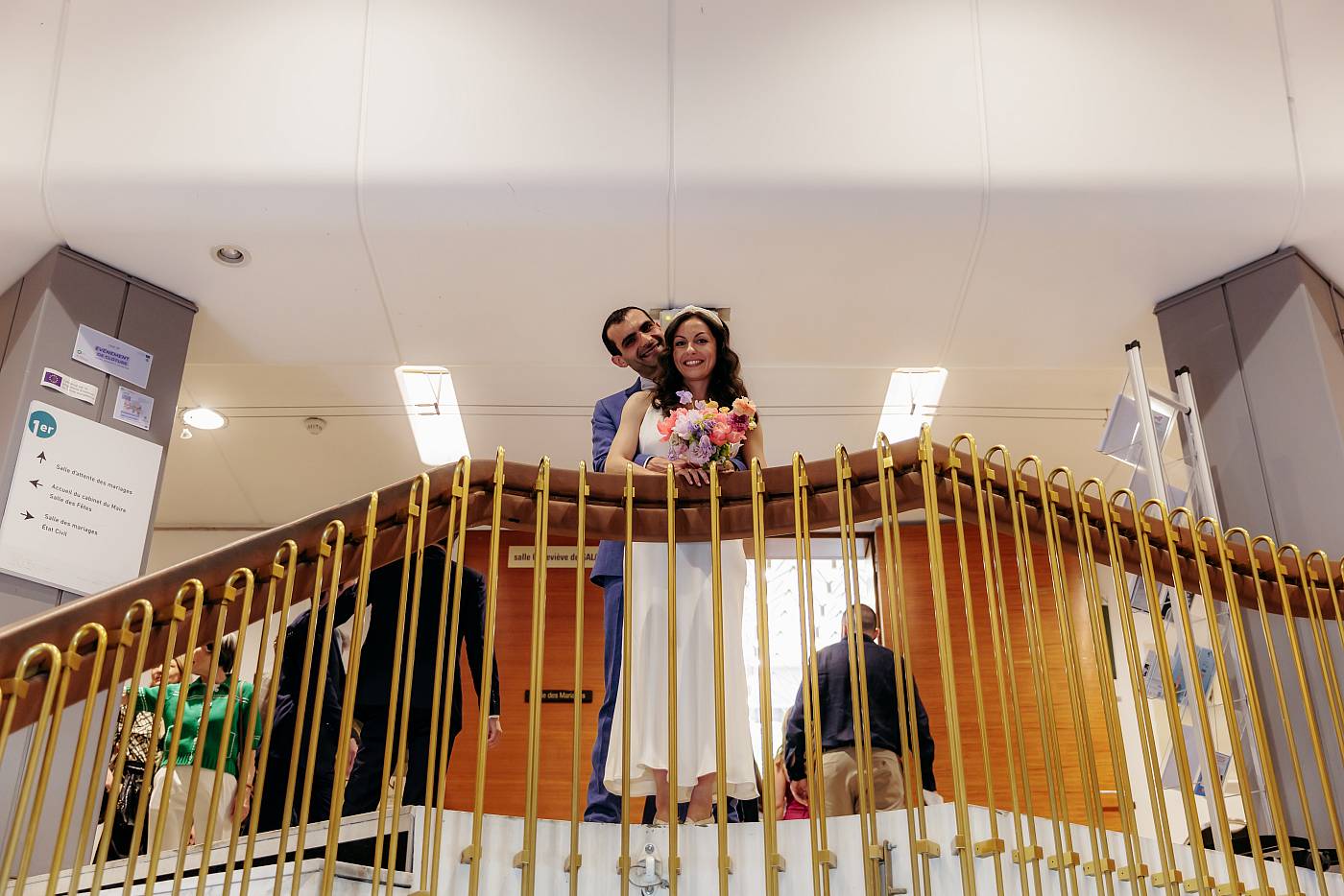 Les mariés dans les bras l'un de l'autre en haut des escaliers de la mairie du 17e arrondissement