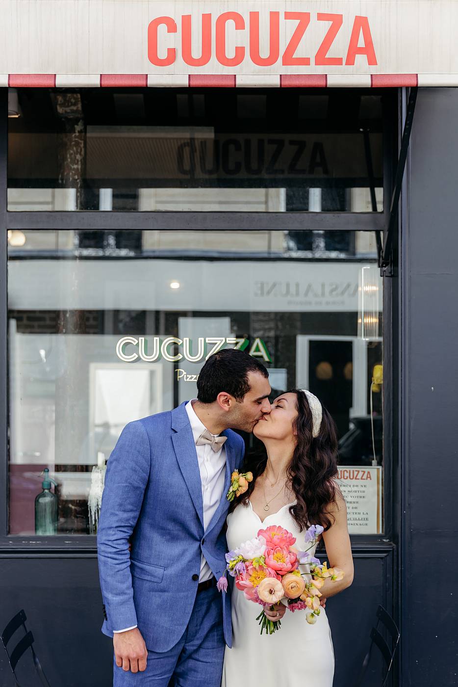 Baiser des mariés devant le lieu de réception Cucuzza à Paris 17ème