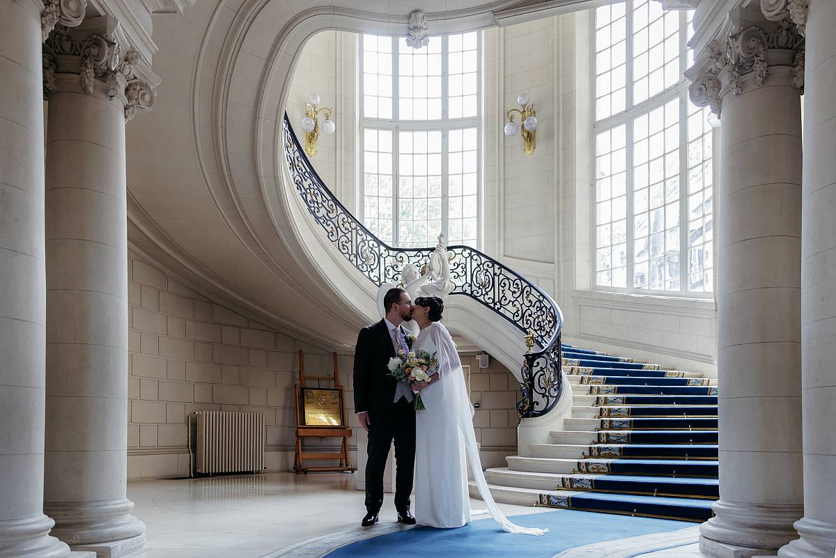 Les mariés s'embrassent dans la belle mairie de Versailles.