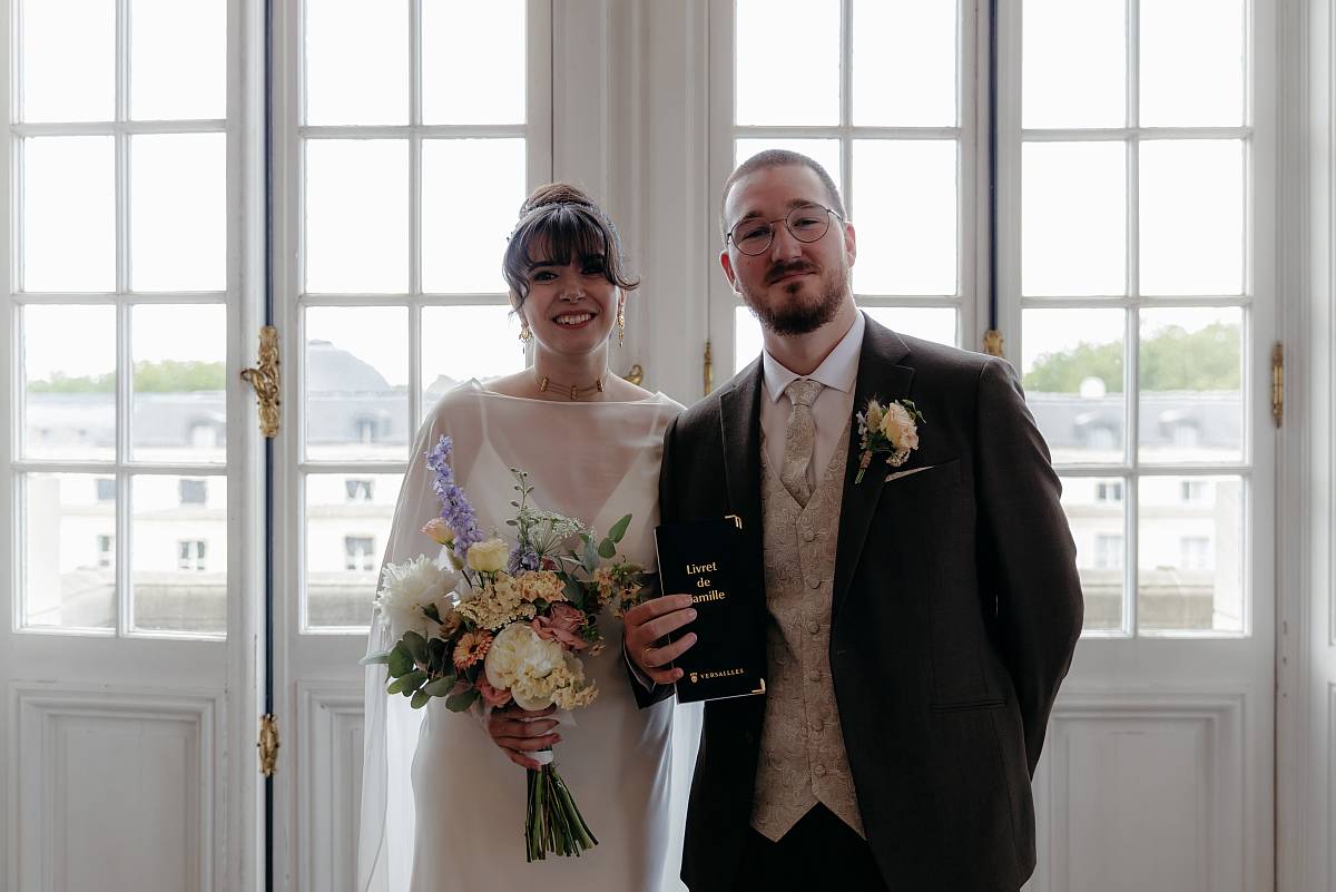 Portrait des mariés avec le livret de famille.