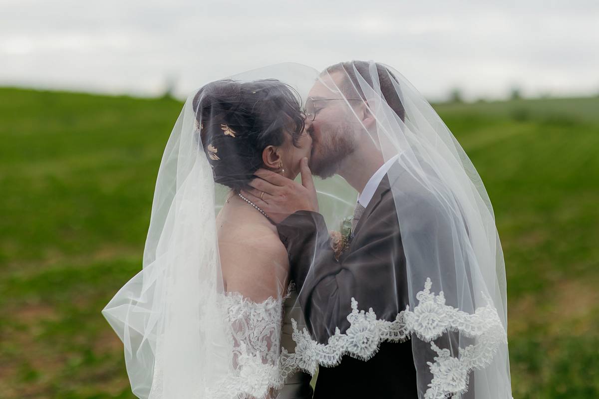 Les mariés s'embrassent sous le voile de la mariée.