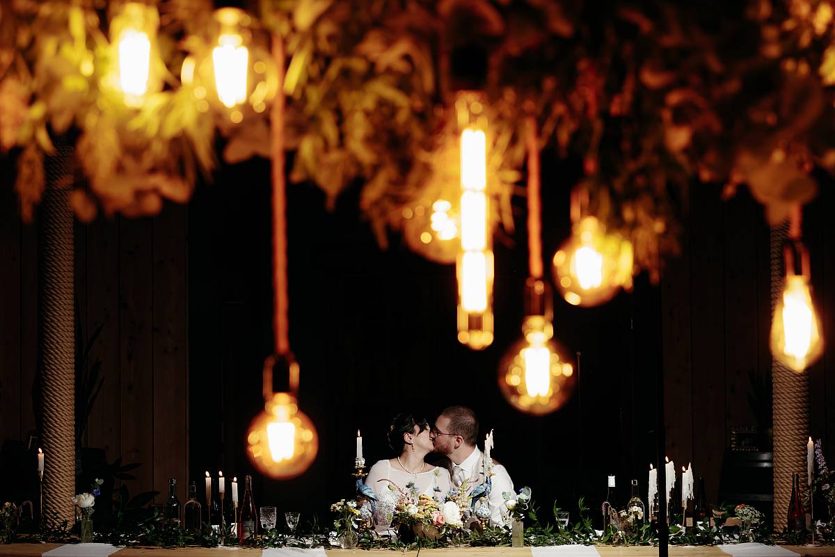 Le baiser des mariés sous les décorations de la salle de réception.
