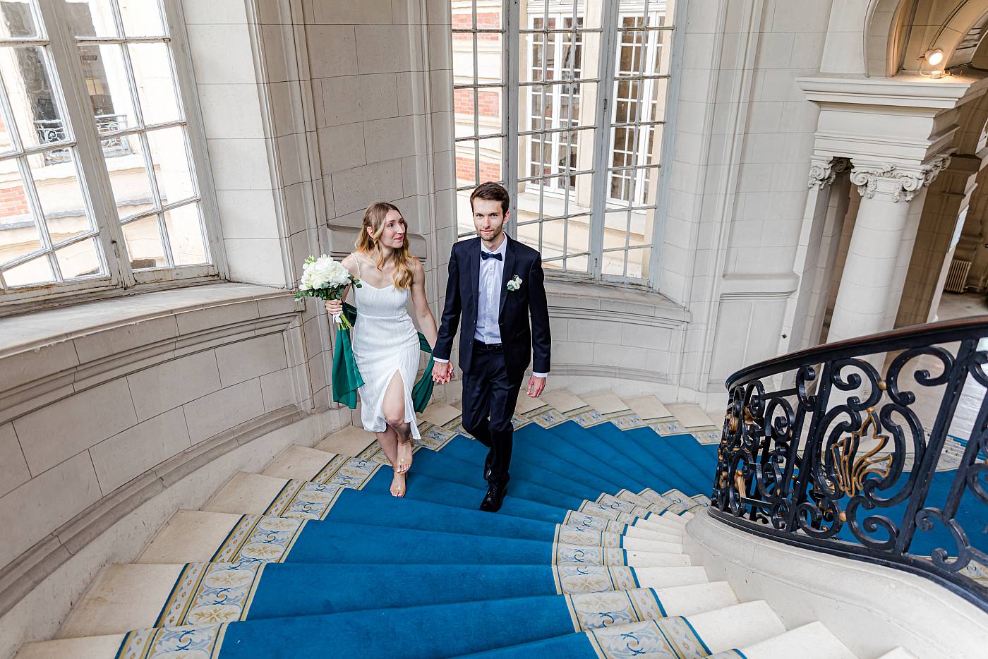 Les mariés main dans la main dans les escaliers de la mairie de Versailles