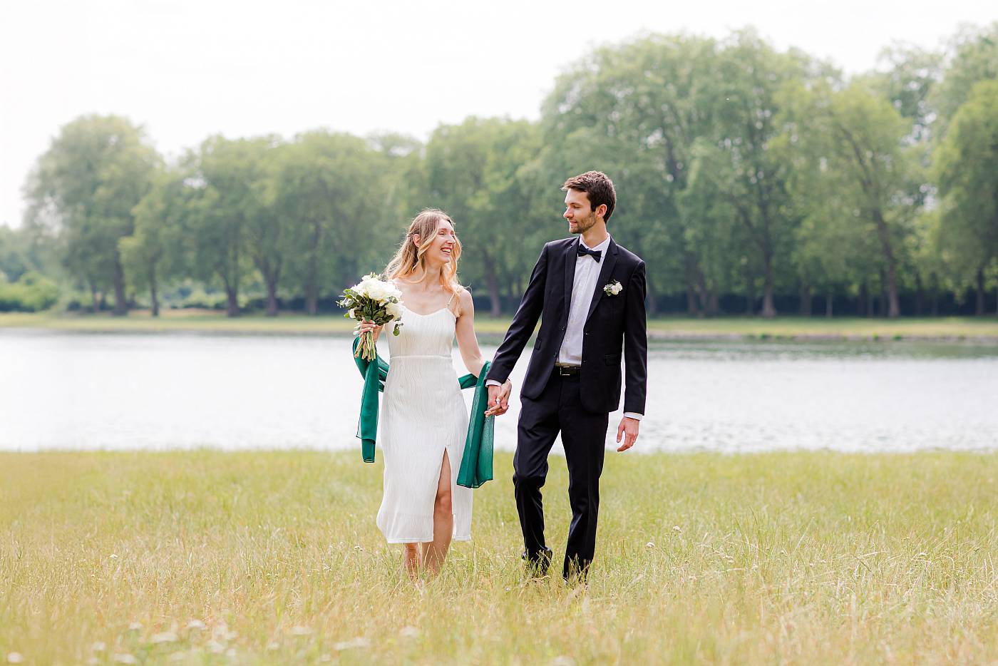 Les mariés marchent main dans la main à la pièce d'eau des Suisses