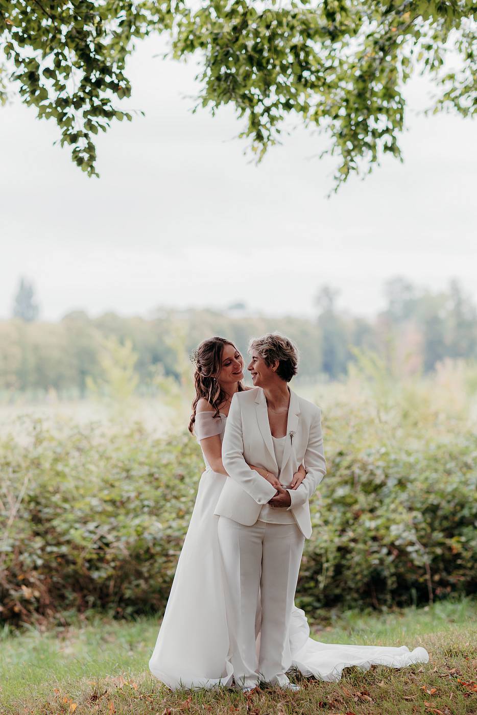 Les mariées dans les bras l'une de l'autre devant la plaine Saint-Antoine à Versailles