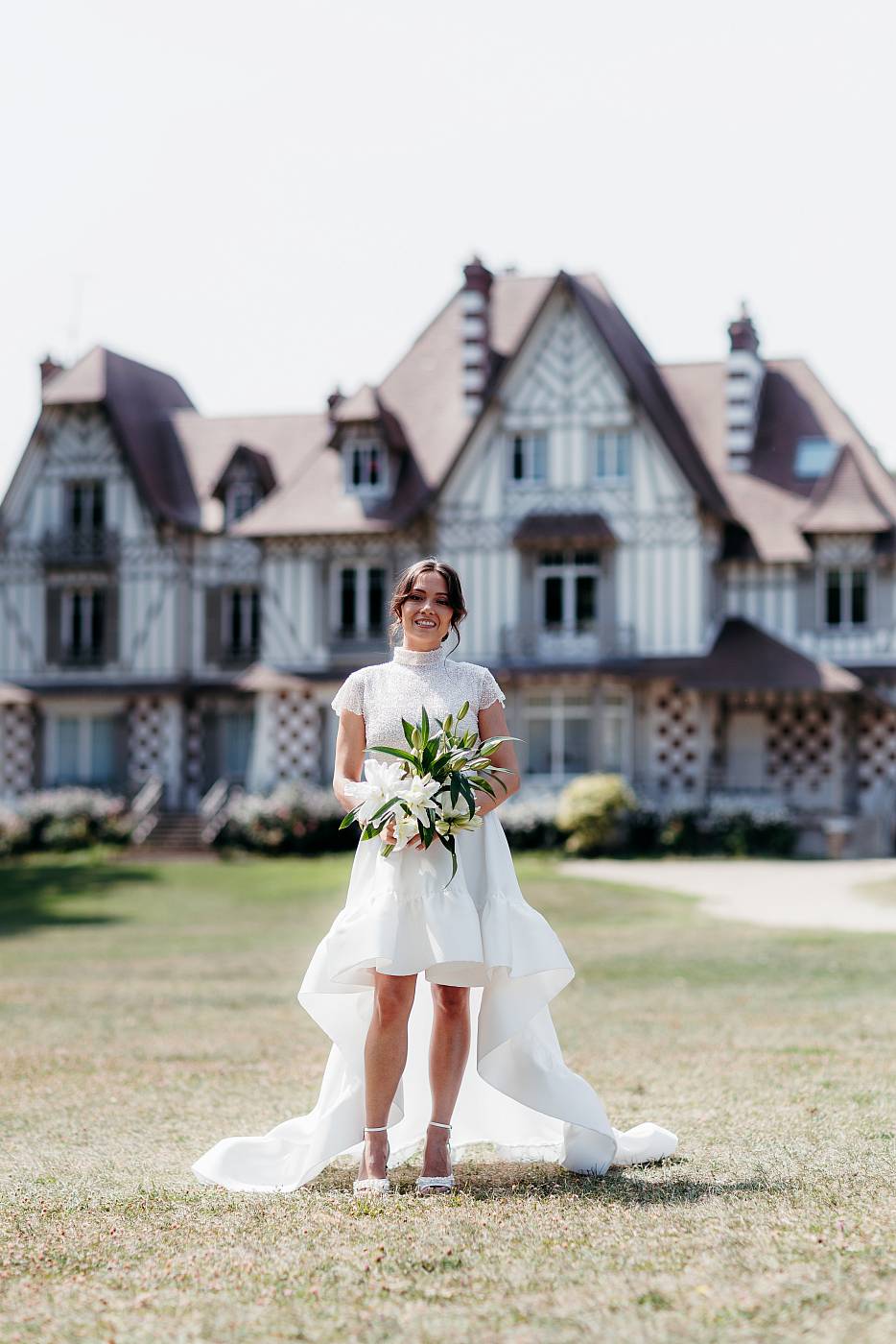 La mariée et son bouquet devant la maison des buissons