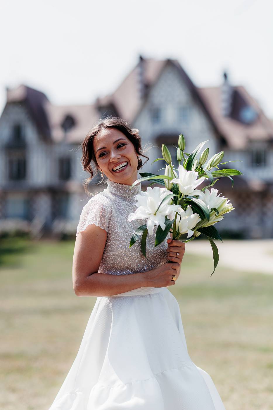 Le sourire de la mariée avec son bouquet devant la maison des buissons