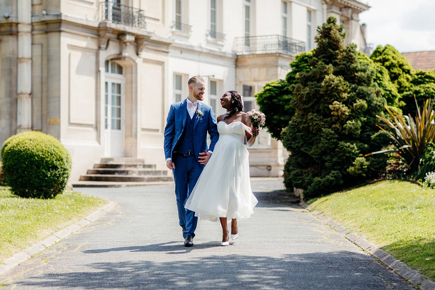 Les mariés marche main dans la main d'un air joyeux dans le parc de la mairie de Plaisir