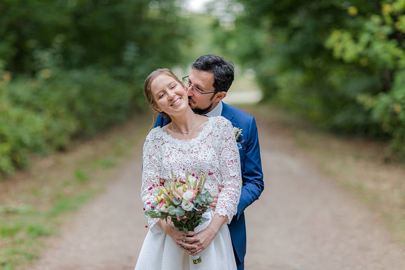 Le marié embrasse le cou de la mariée à Marly-le-Roi dans les Yvelines