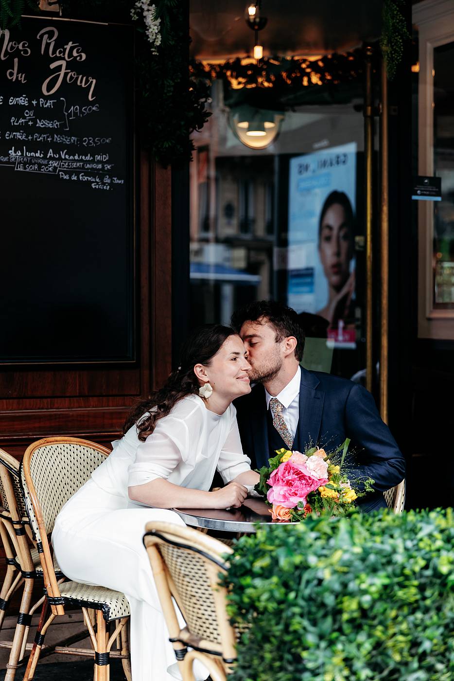 Baiser sur la joue de la mariée sur la terrasse d'un café à Paris