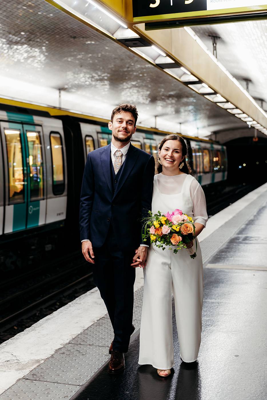 Les mariés mains dans la main sur le quai du métro