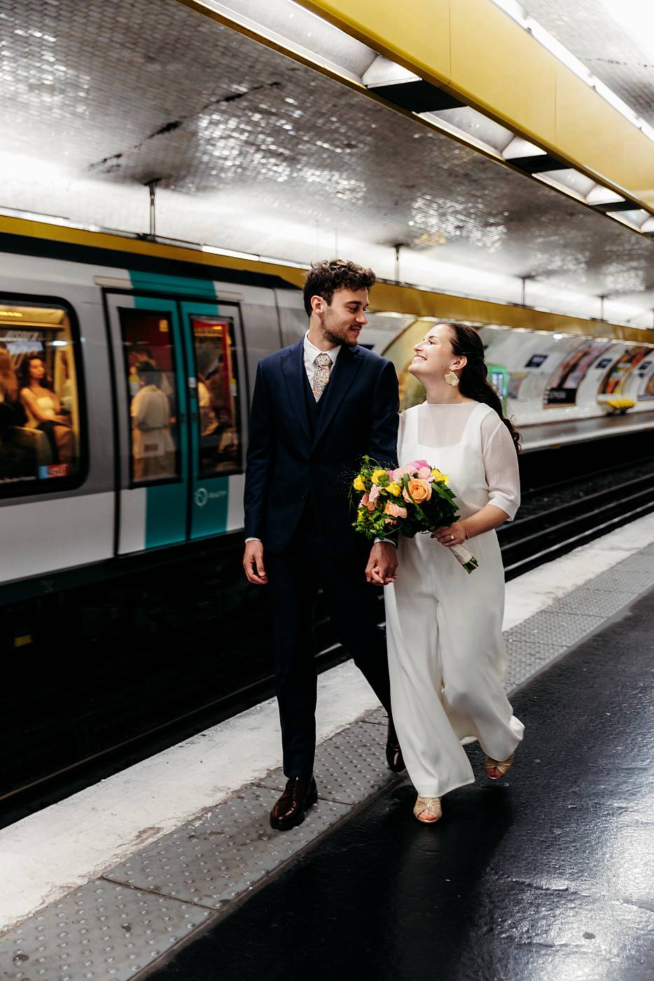 Les mariés se promènent main dans la main sur le quai du métro