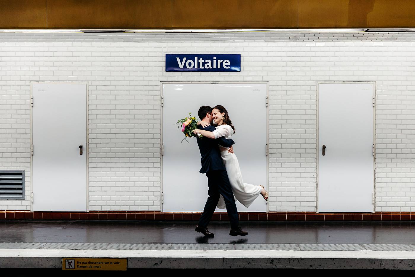 Le marié fait tourner la mariée dans ses bras sur les quais du métro