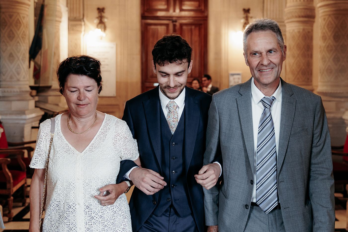 Le marié entre dans la salle des mariages accompagné de ses parents