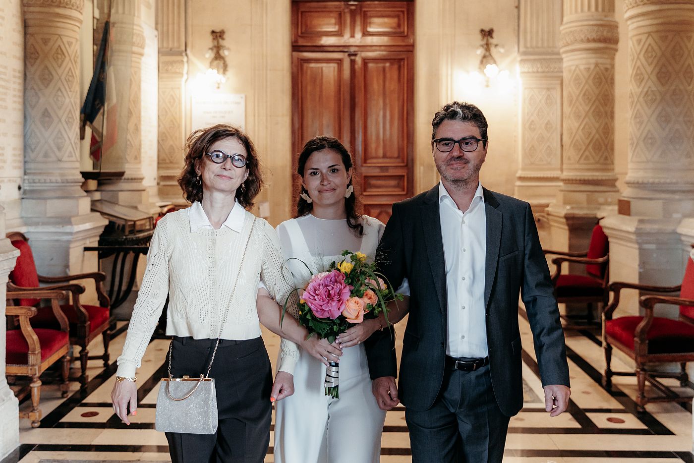 La mariée entre dans la salle de cérémonie accompagnée de ses parents