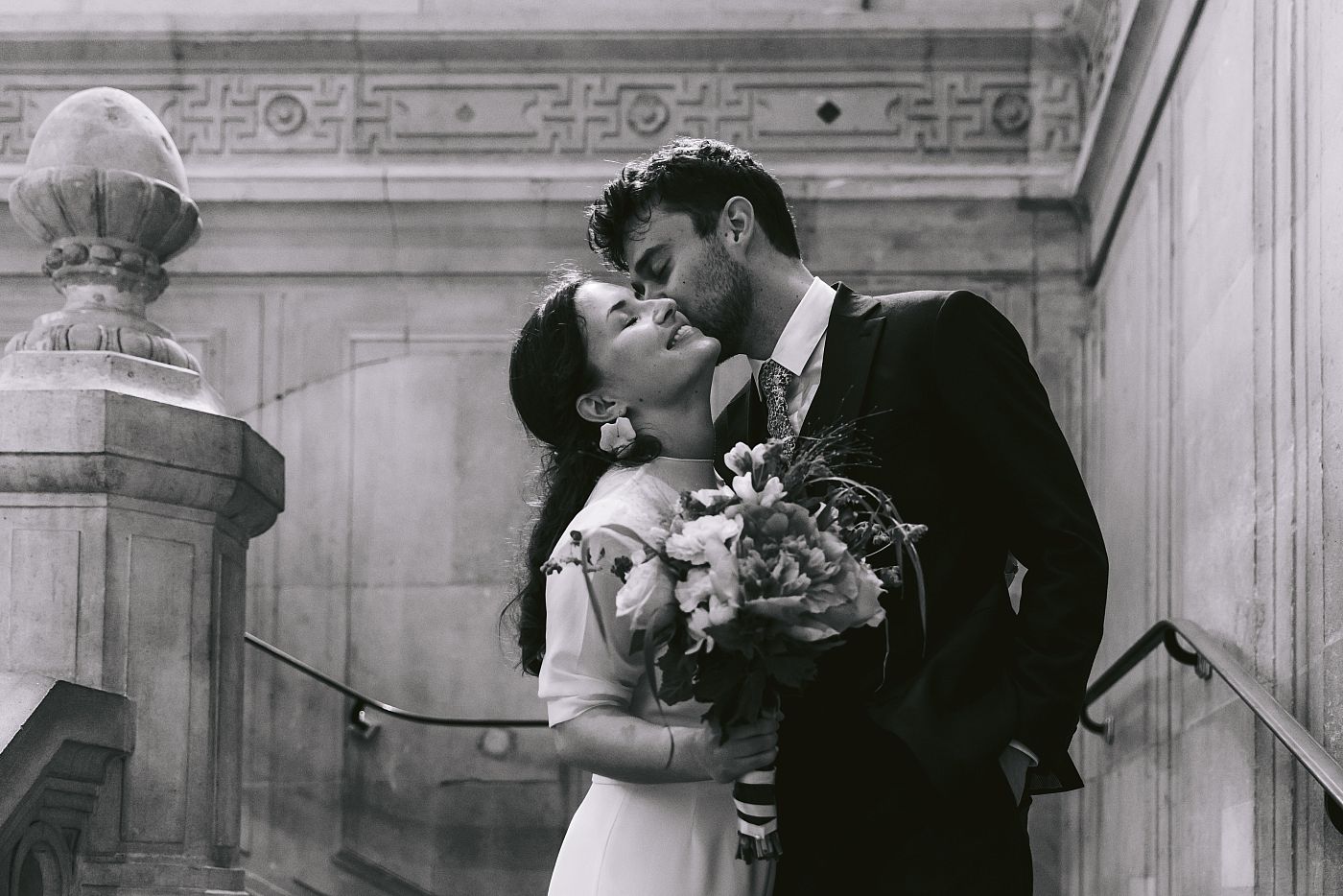 Baiser des mariés dans les escaliers de la mairie de Paris dans le 11e arrondissement