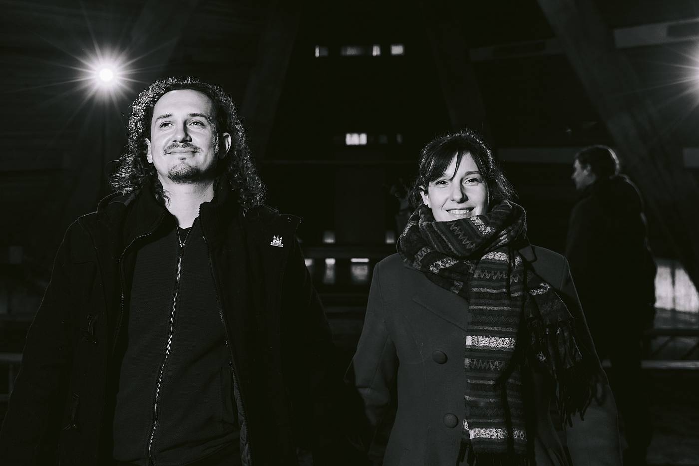 Les mariés sortent de la chapelle tandis que les flash crépitent en arrière-plan